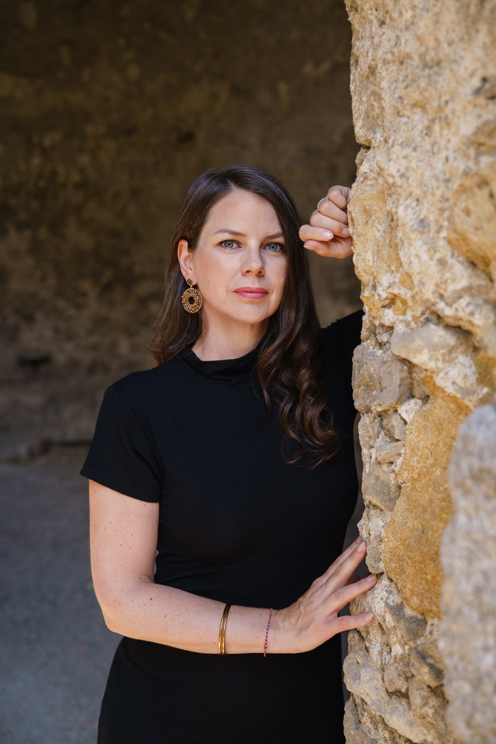 Cornelia Fiechtl mit der Hand an einer Steinmauer